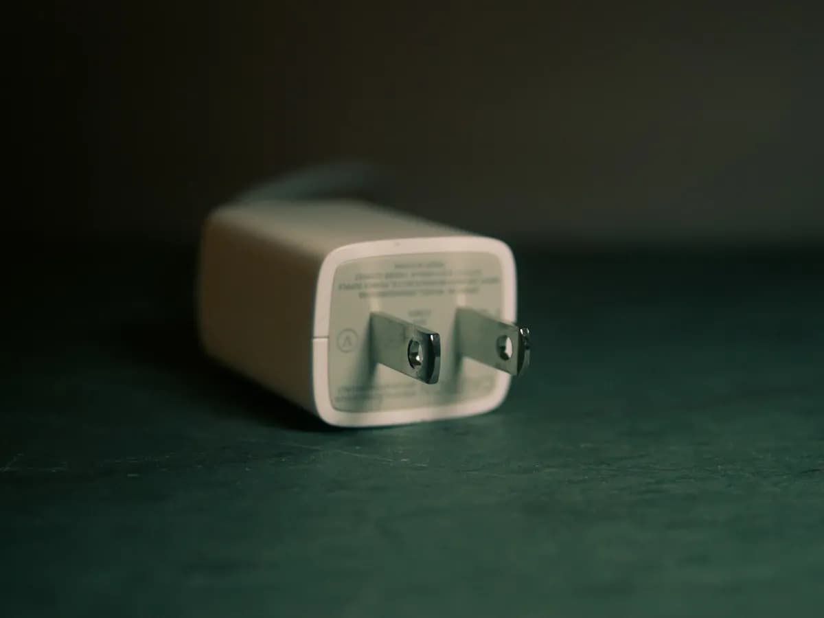 A compact wall charger on a dark green surface